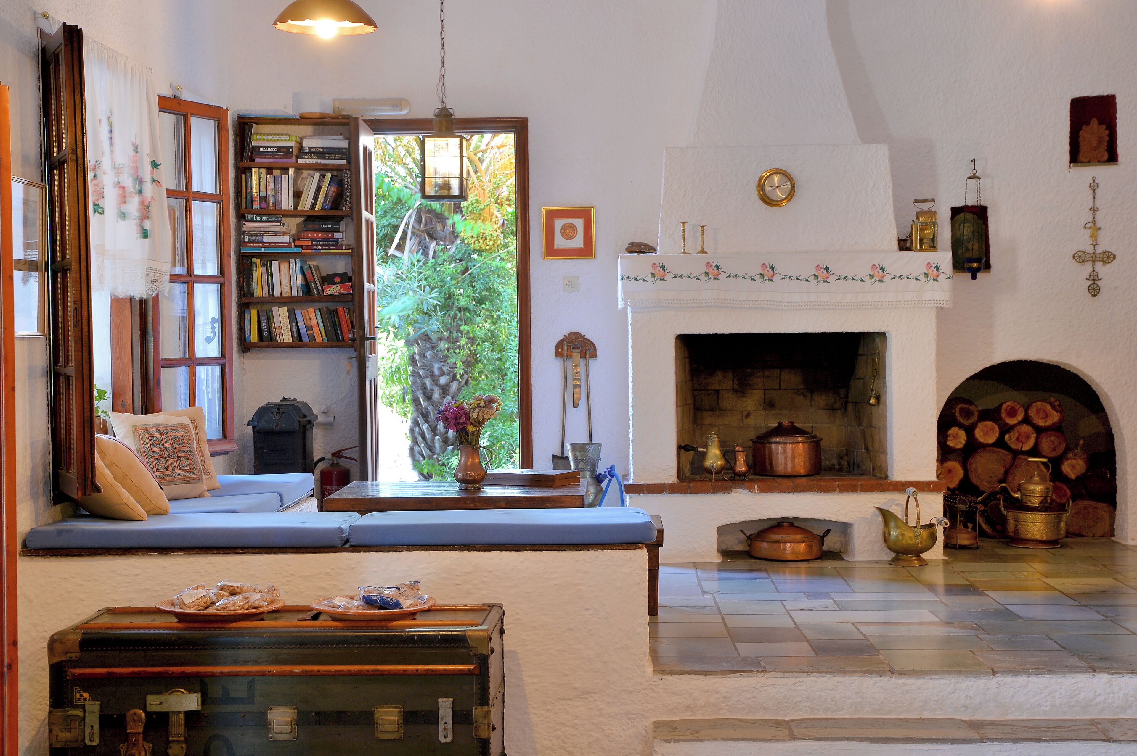 Una sala de estar acogedora con chimenea, una estantería y un ventanal con vistas a la vegetación.