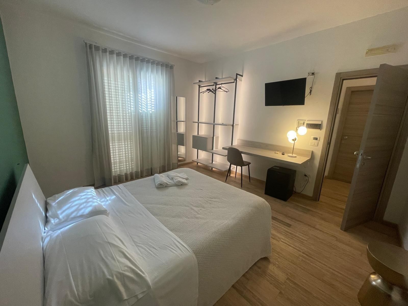 Une chambre d’hôtel comprenant un lit, un bureau, une chaise, une télévision et une armoire.