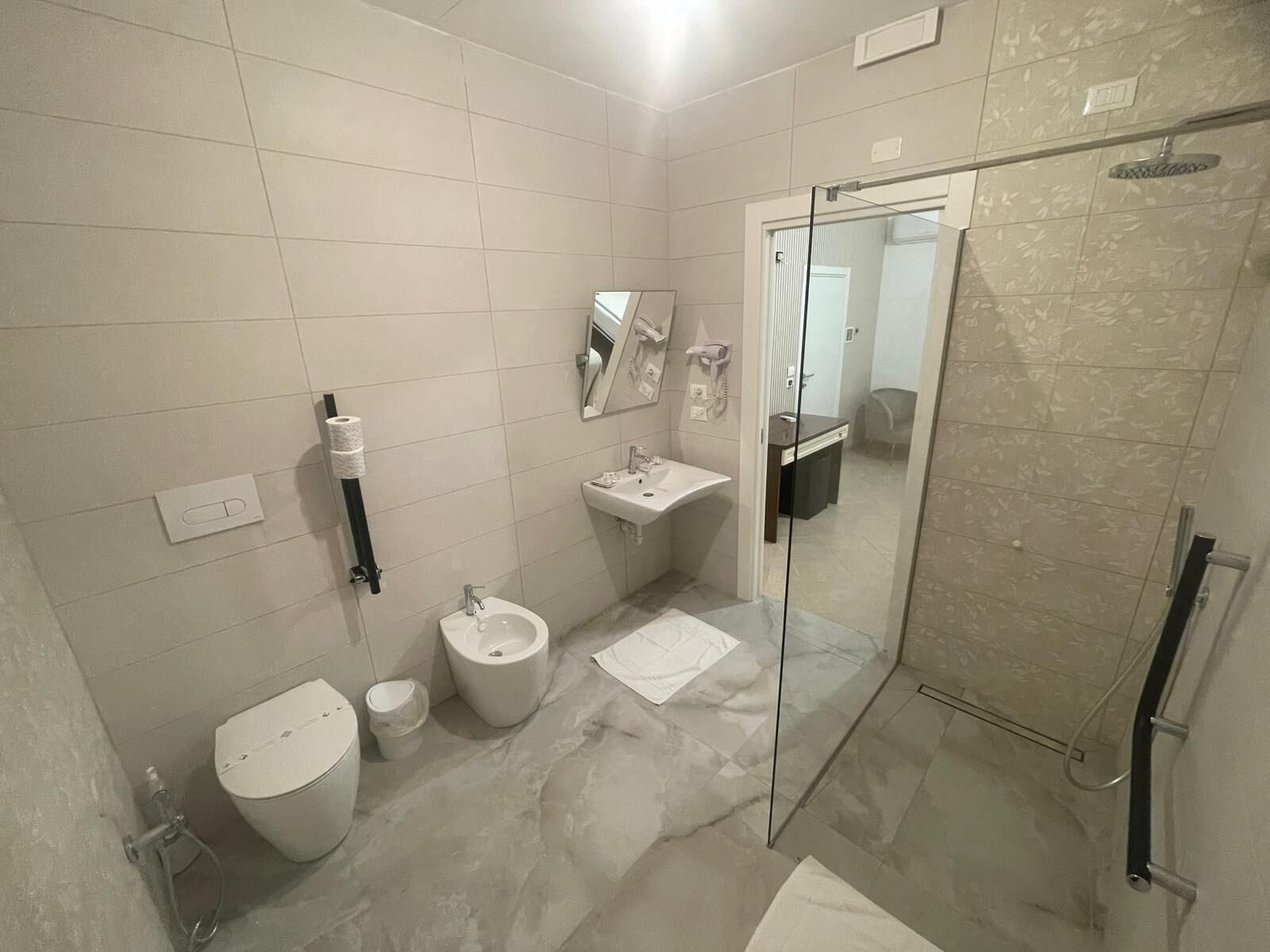 Un bany amb vàter, bidet, rentamig i plat de dutxa de vidre.