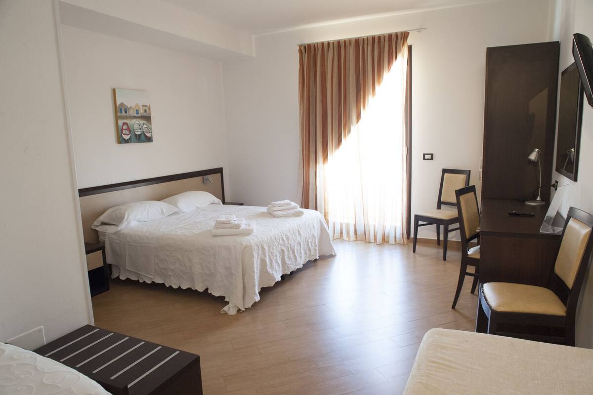 Una habitación de hotel con una cama, un escritorio, una silla y un televisor.
