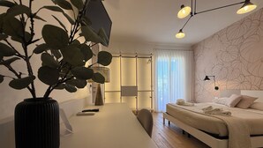 A modern hotel room with a bed, bedside table, and a large potted plant.