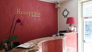 A reception area with a red wall, a clock, and a lamp.