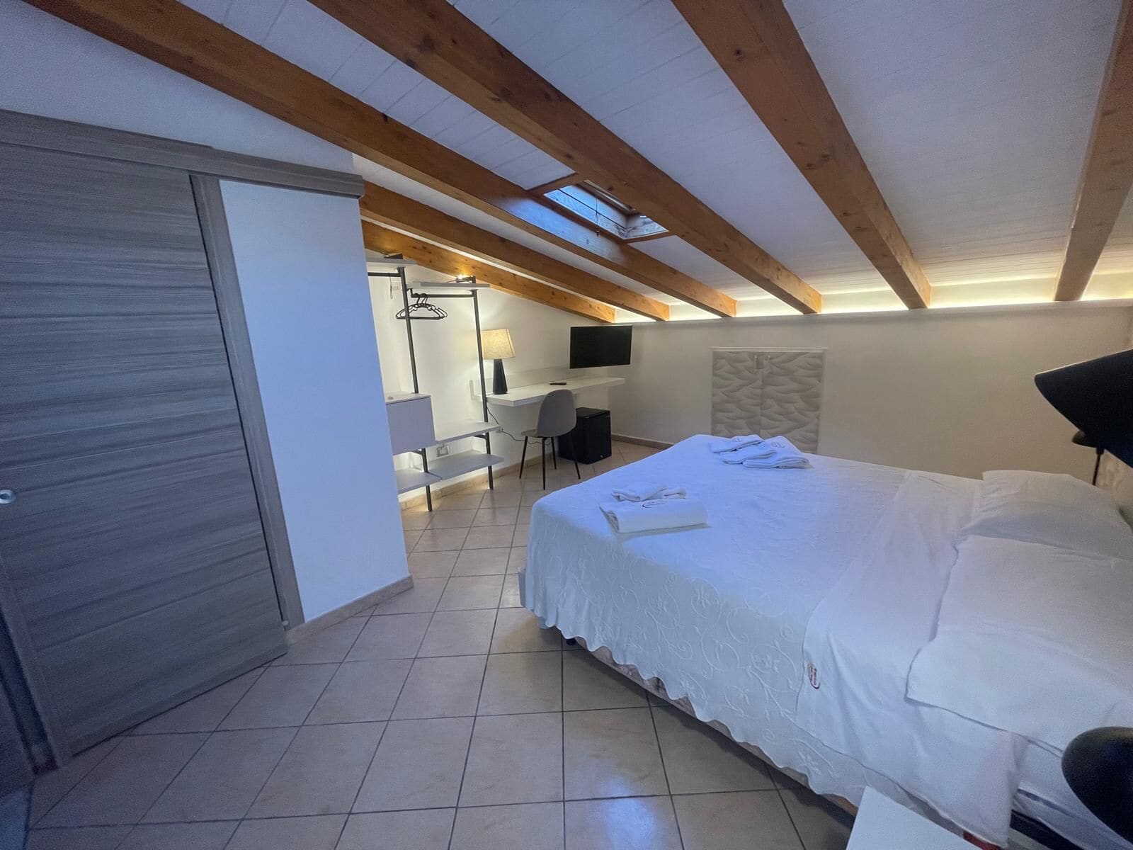Une chambre moderne avec un grand lit, un bureau et une télévision.