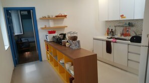 Une cuisine compacte équipée d’un four à micro-ondes, d’une machine à café et d’étagères contenant des ustensiles de cuisine.