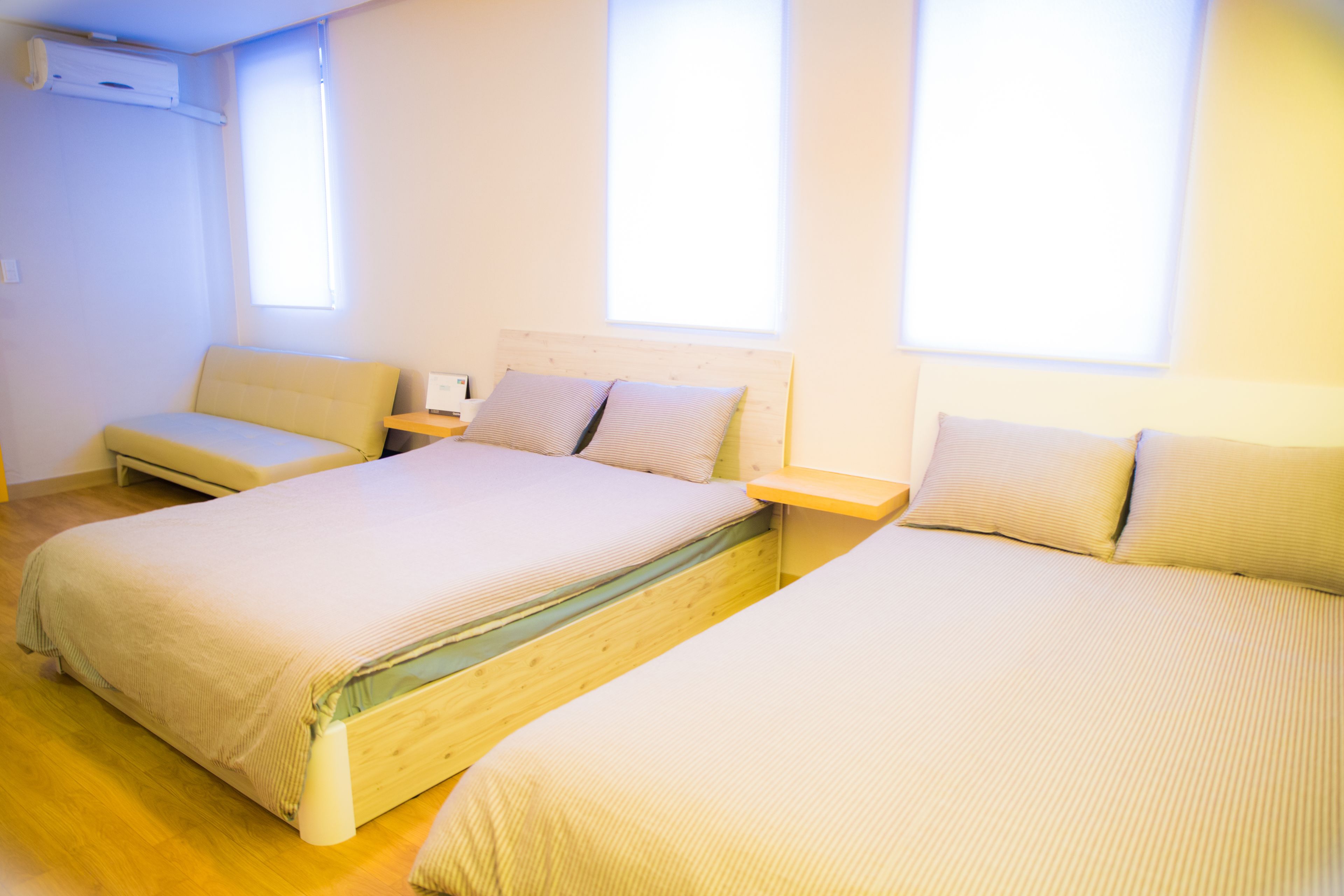 A room with two beds, a sofa, and a bedside table.