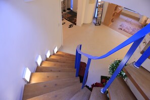 Un escalier en bois avec des rampes bleues menant à un palier.