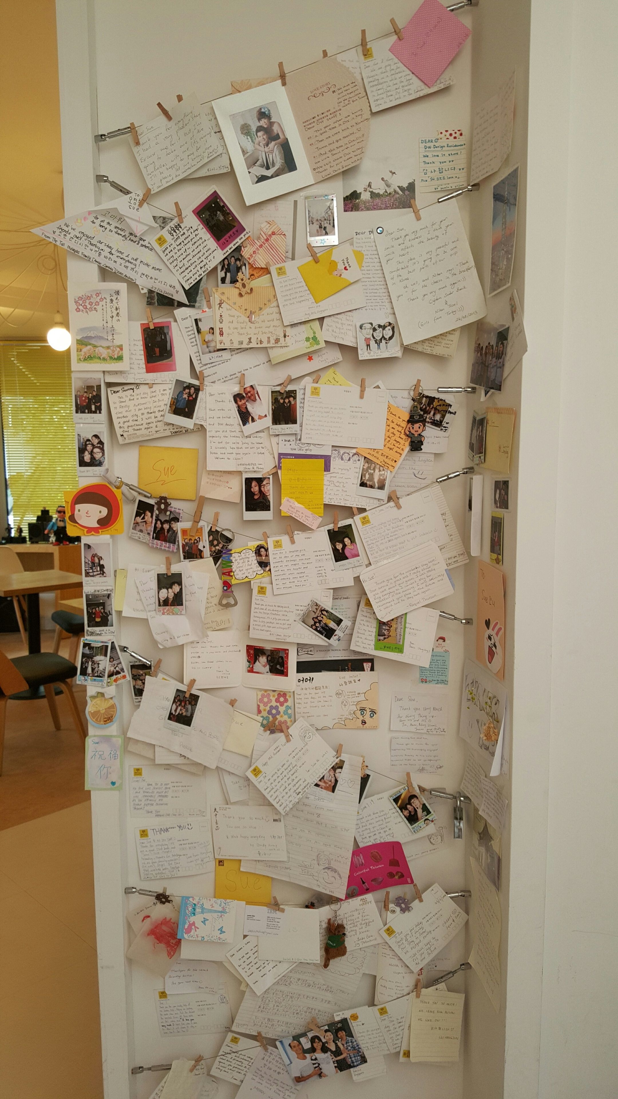 A bulletin board with various notes, photos, and drawings pinned to it.