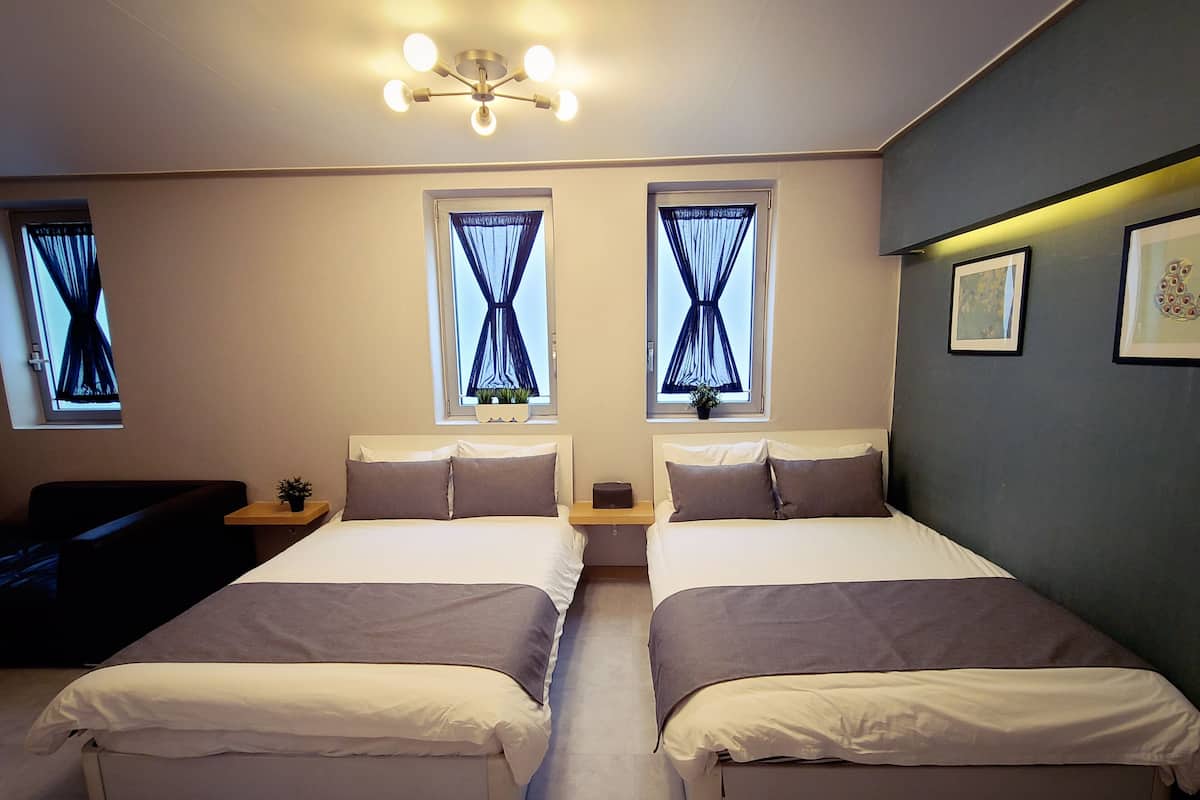 A double room with two beds, a small seating area, and a ceiling light fixture.