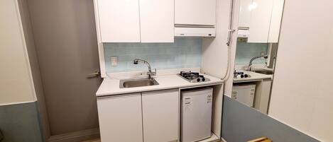 A compact kitchen with a sink, stove, and a small refrigerator.