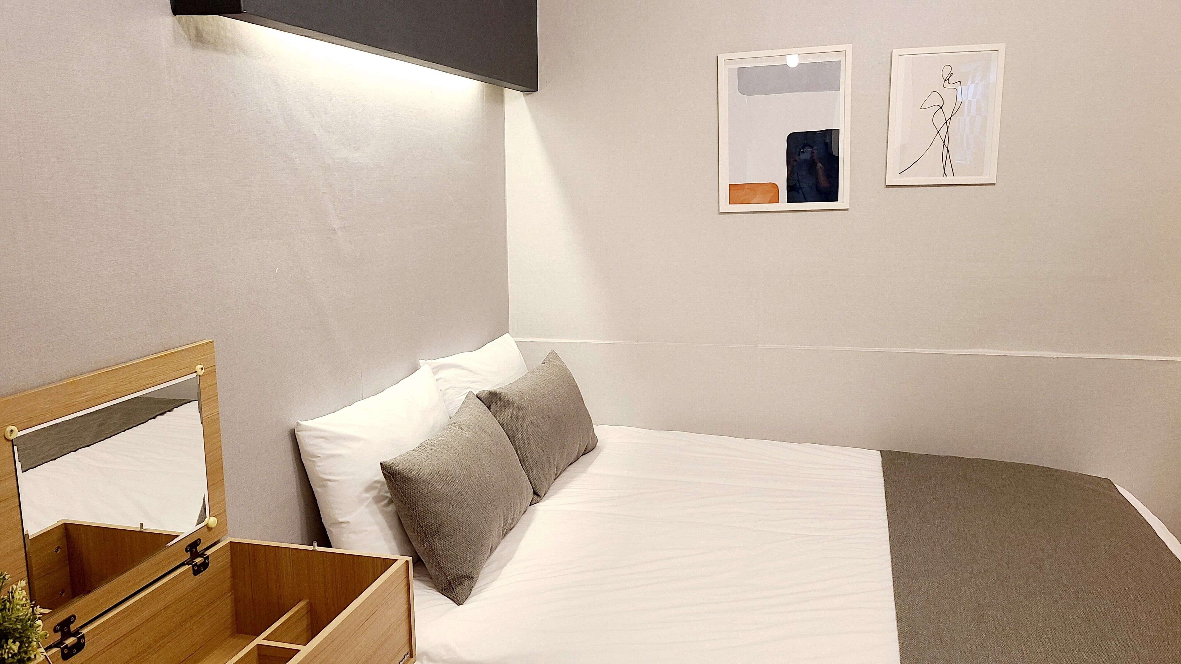 Et pænt og ryddeligt hotelværelse med en seng, en trækommode, et spejl og to billeder hængende på væggen.