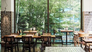 Un restaurante con ventanas amplias, mesas y sillas de madera.