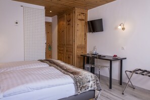 Quarto com cama, escrivaninha, televisão e guarda-roupa de madeira.