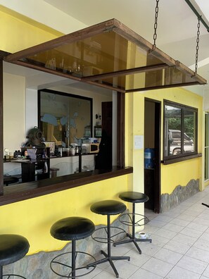 A bar area with stools, a counter, and a hanging light fixture. - Dream Hill Condos & Spa (Puerto Galera)