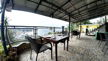 Un área de comedor al aire libre con una mesa para dos, sillas de mimbre y vista al océano.
