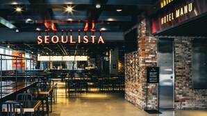A modern restaurant with a neon sign reading "SEOULISTA" and a "HOTEL MANU" sign.