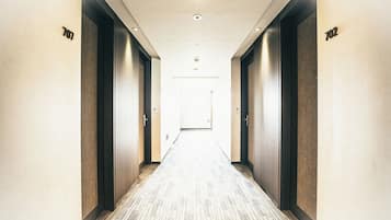 A hotel hallway with doors numbered 707 and 702, leading to a room.