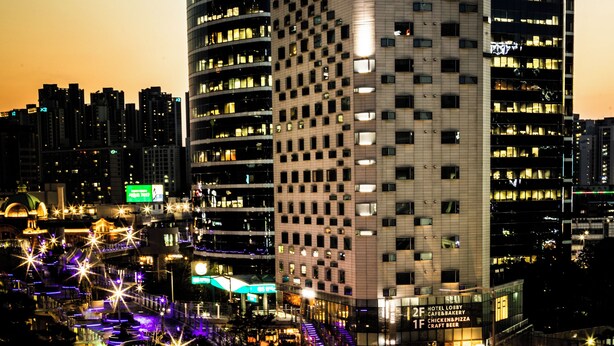 A modern hotel building with multiple floors, a prominent sign, and a well-lit facade.