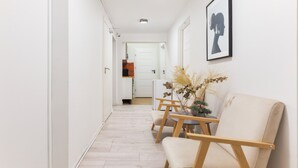 A hallway with a wooden floor, a beige sofa, and a small table with a vase of dried plants. - Moon Hostel Warszawa (Warsaw)