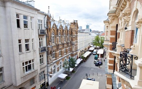 A street view of a city with historic buildings, a café-lined street, and a clear sky.