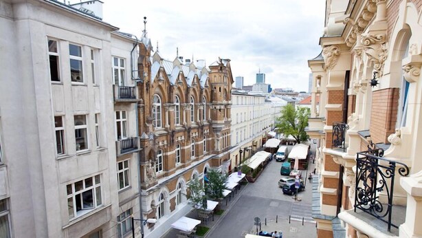 A street view of a city with historic buildings, a café-lined street, and a clear sky. - Moon Hostel Warszawa (Warsaw)