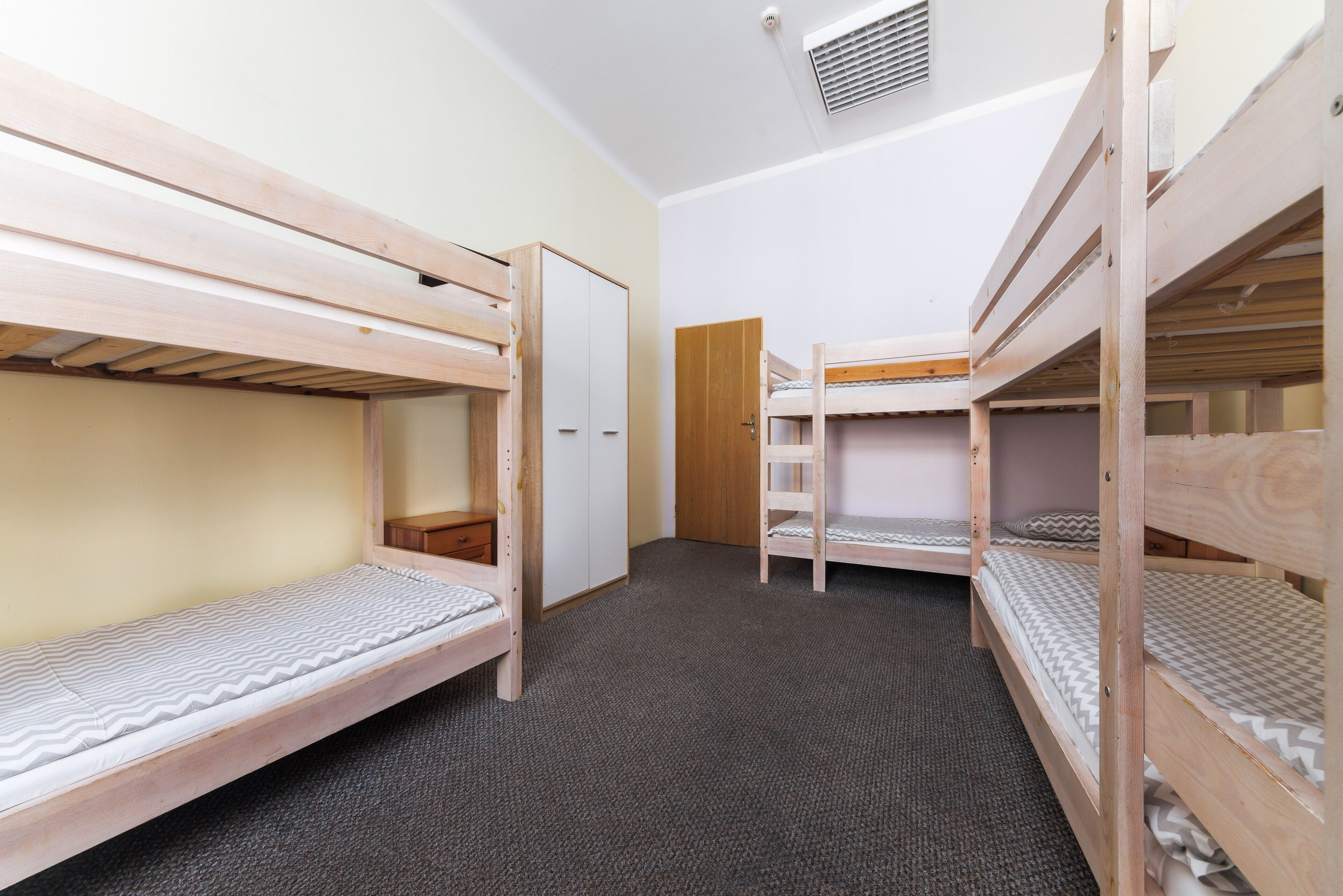 Ein Zimmer mit drei Etagenbetten, einem Kleiderschrank und einer Tür.