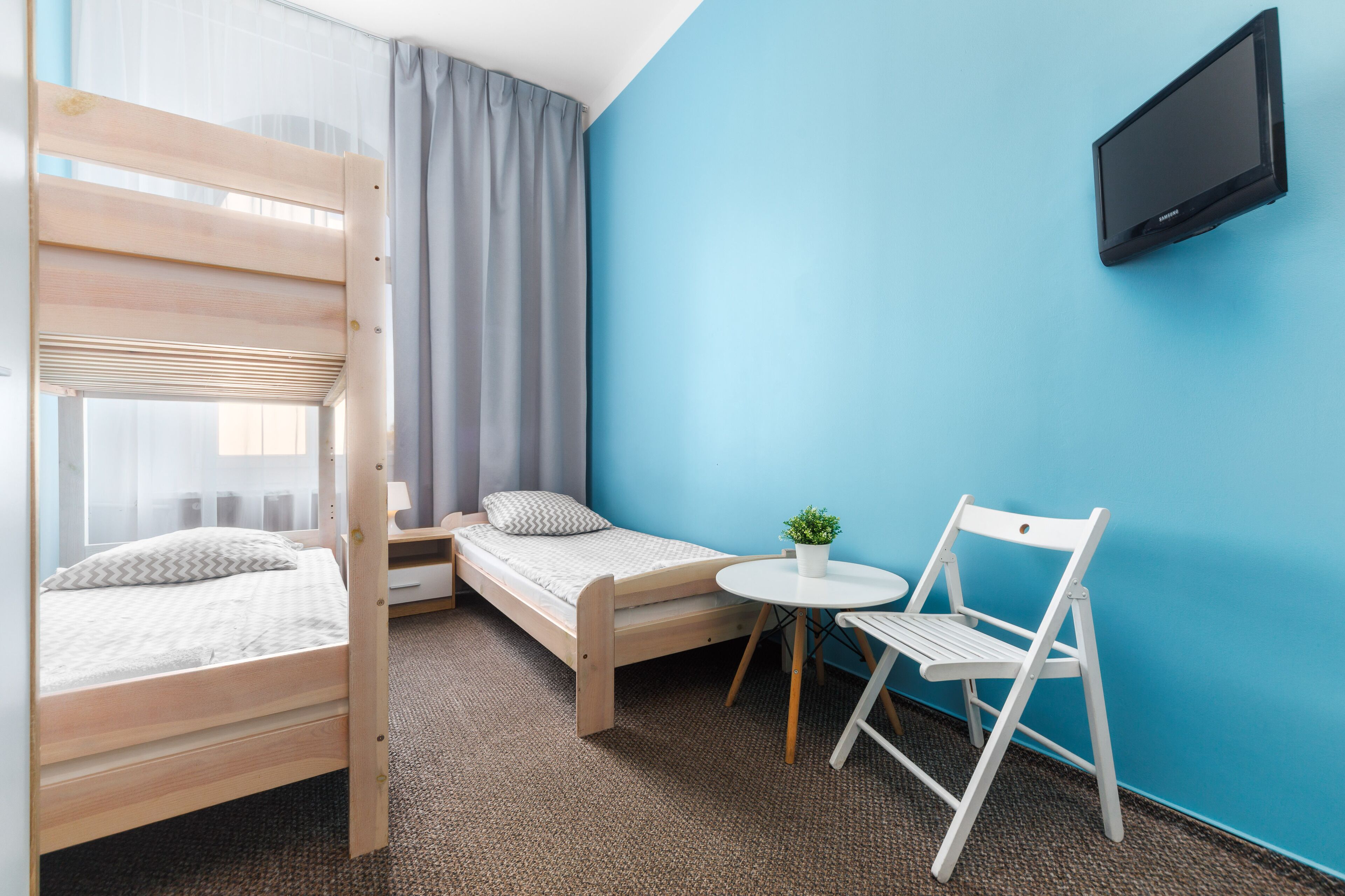 A compact room with a bunk bed, a small table with a chair, and a TV mounted on the wall.