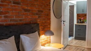 A bedroom with a brick wall, a bed with white bedding, a bedside lamp, and a pendant light. - Moon Hostel Warszawa (Warsaw)