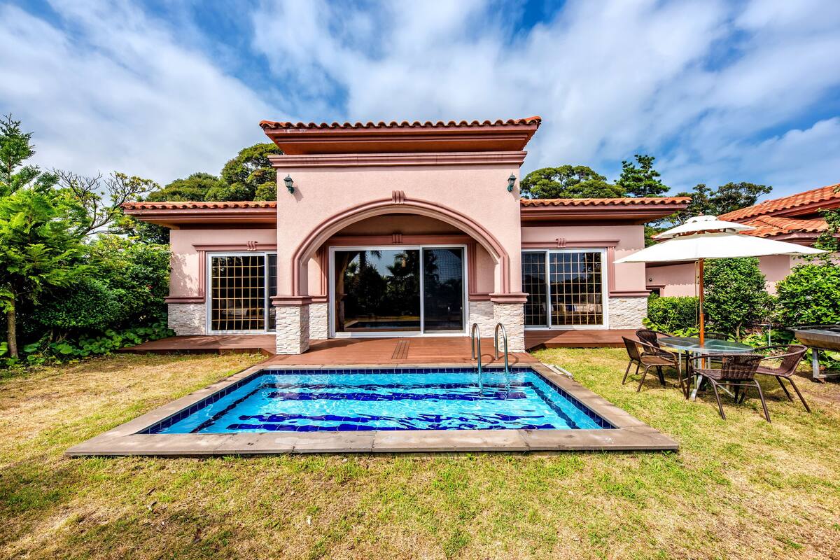 A house with a swimming pool, patio furniture, and a covered outdoor seating area.