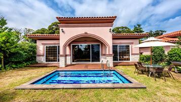 A house with a swimming pool, patio furniture, and a covered outdoor seating area.