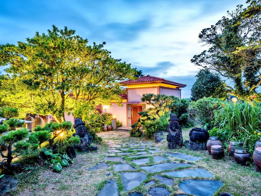 A pathway leading to a house surrounded by lush greenery and stone steps.