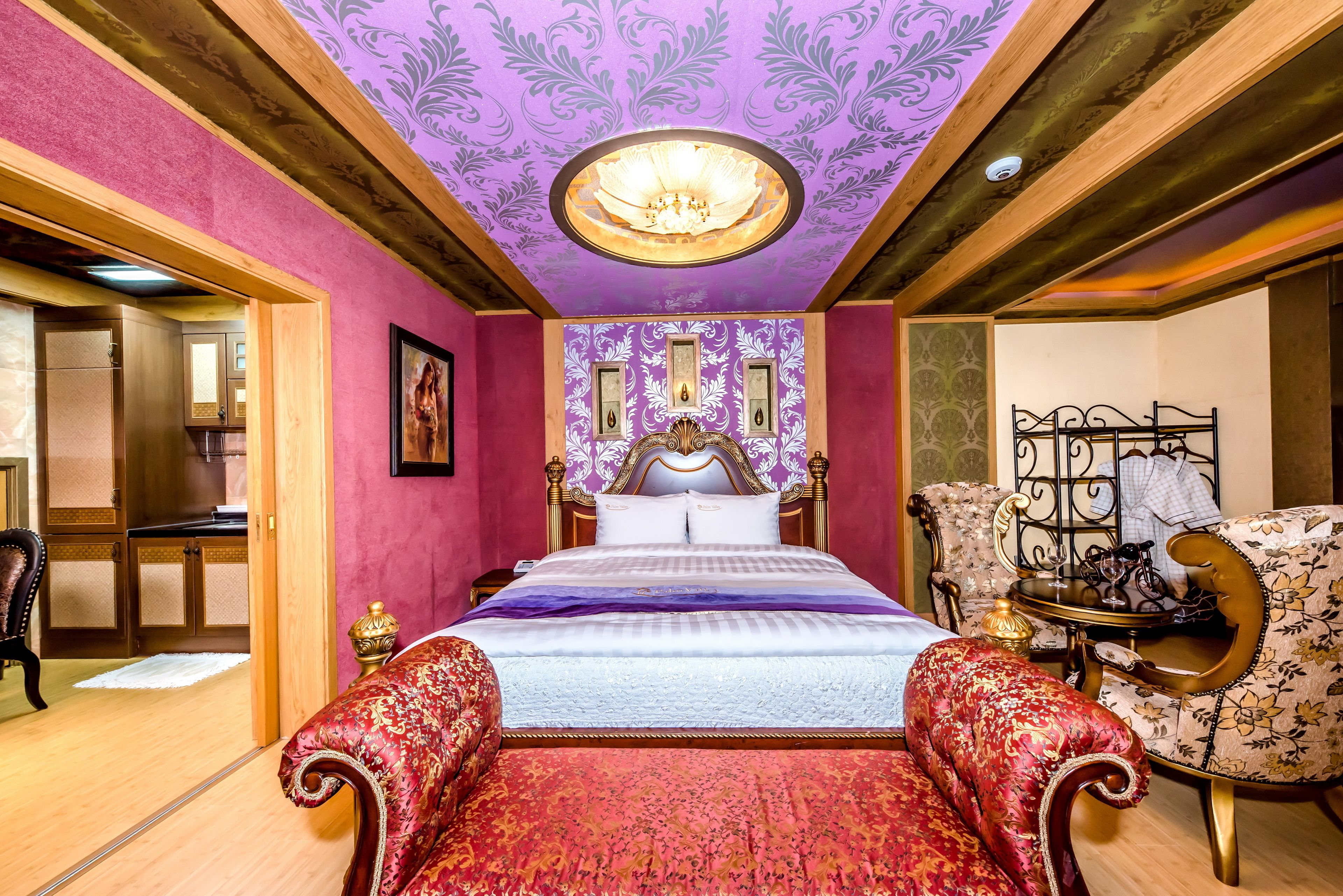 A bedroom with a large bed, ornate headboard, and a chandelier.