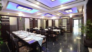 Un espace repas avec des tables disposées pour accueillir plusieurs personnes, un design moderne au niveau du plafond et un sol propre et bien entretenu.