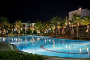 A swimming pool with a curved design, surrounded by palm trees and lounge chairs. - Amphoras Blu Ultra All Inclusive Adults Only (Sharm El Sheikh)