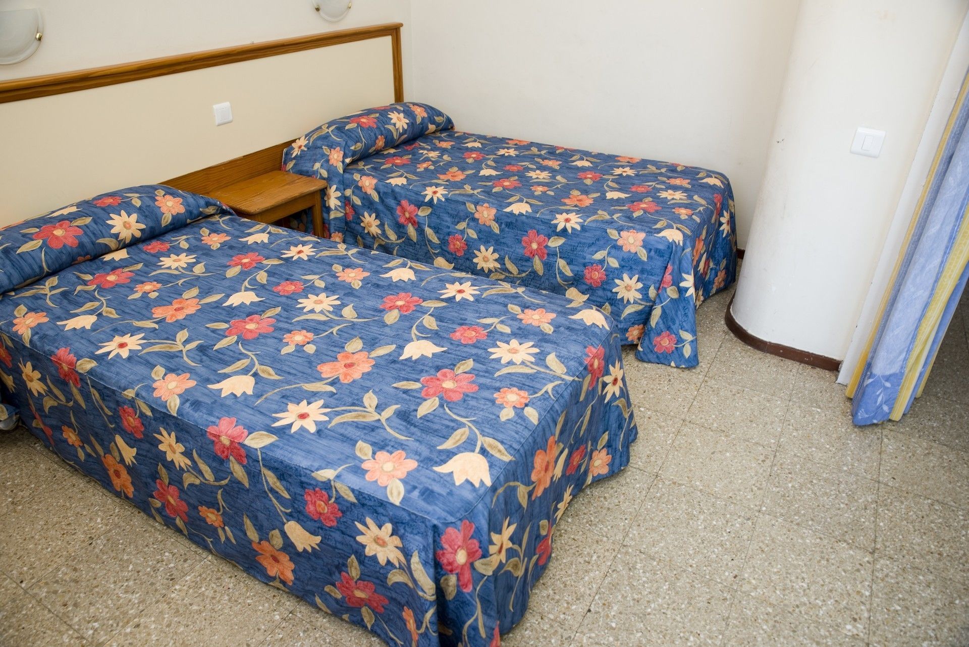Habitación con dos camas, cada una con ropa de cama estampada con motivos florales.