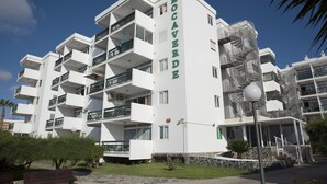 A multi-story hotel with balconies, a stone facade, and a clear sky. - Roca Verde (San Bartolomé de Tirajana)