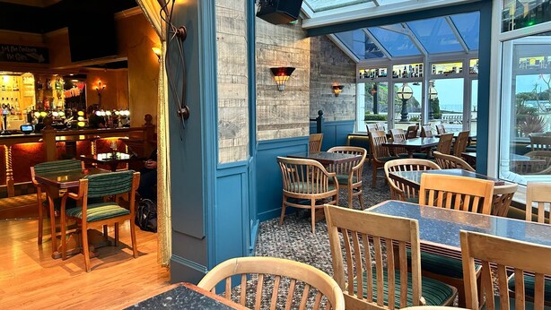 A restaurant with a bar area, wooden chairs, and tables. - The Heritage Hotel (Torquay)