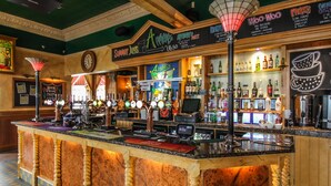 A bar area with a counter, multiple taps, and a variety of bottles and glasses. - The Heritage Hotel (Torquay)