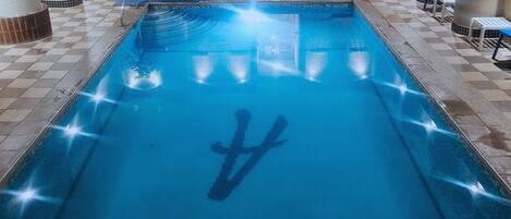 An indoor swimming pool with a clear water logo, tiled walls, and a checkered floor pattern.