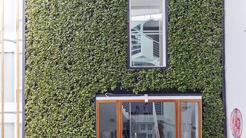 A restaurant with outdoor seating, a glass door entrance, and a vertical garden wall.