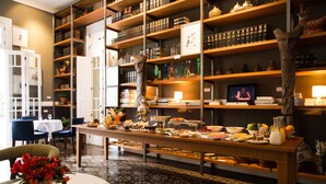 A dining area with a long table set for a meal, surrounded by shelves with books and decorative items. - Hotel B (Lima)