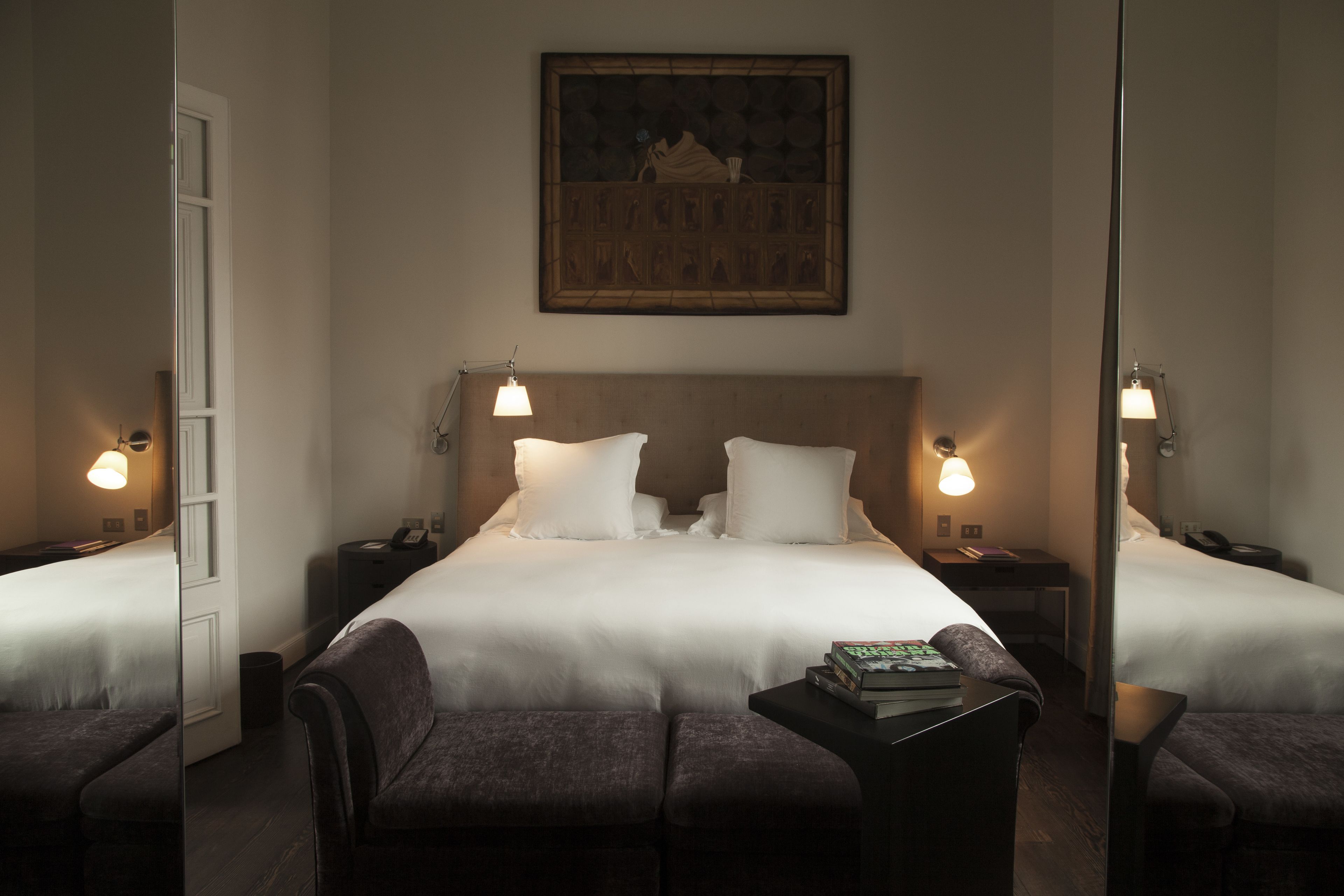 A hotel room with a large bed, two bedside tables with lamps, a small desk, and a chair.