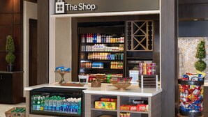 A store named 'The Shop' with shelves stocked with beverages, snacks, and packaged goods.