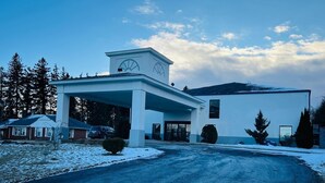 A building with a covered entrance, a clock tower, and a snow-covered driveway.