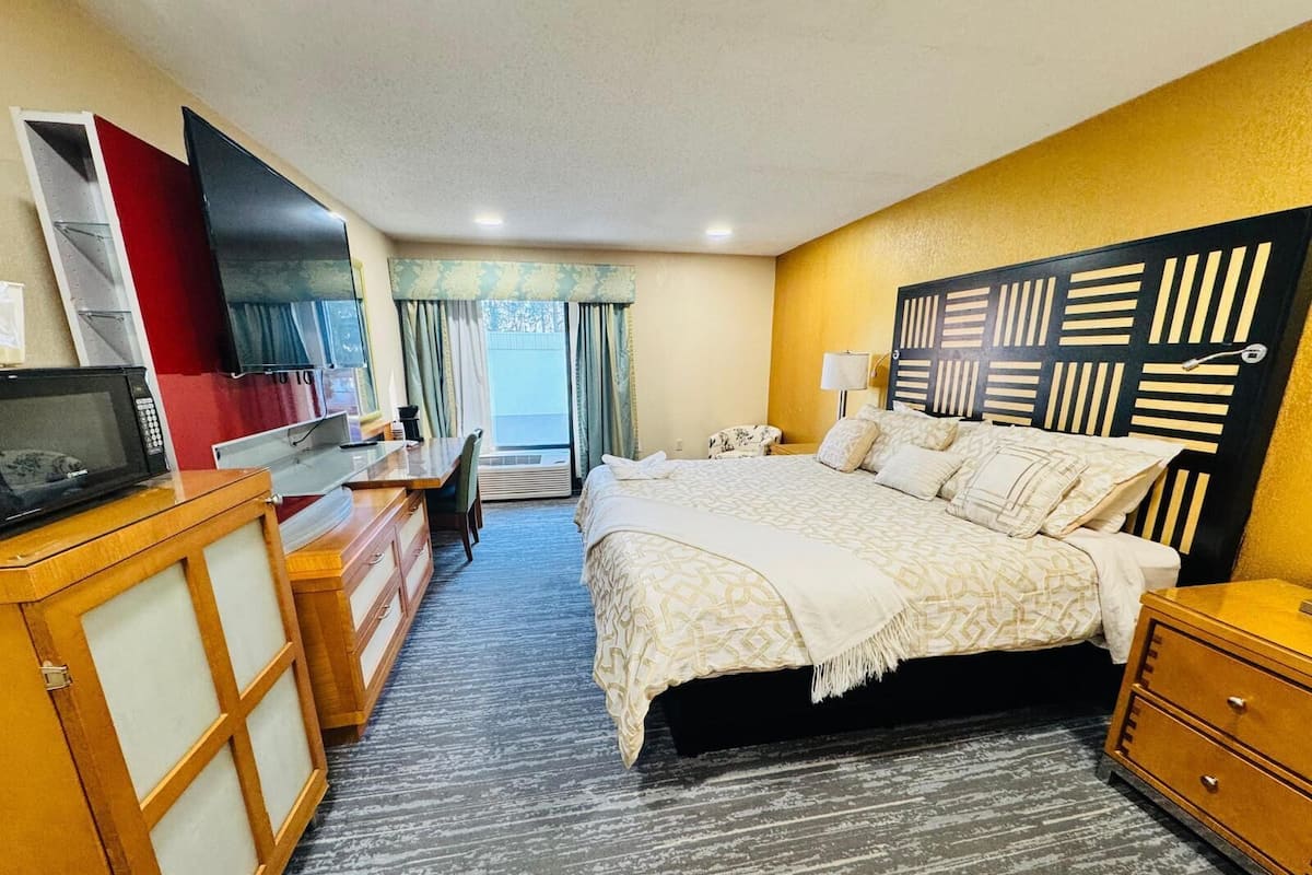 A hotel room with a bed, desk, chair, and a television.