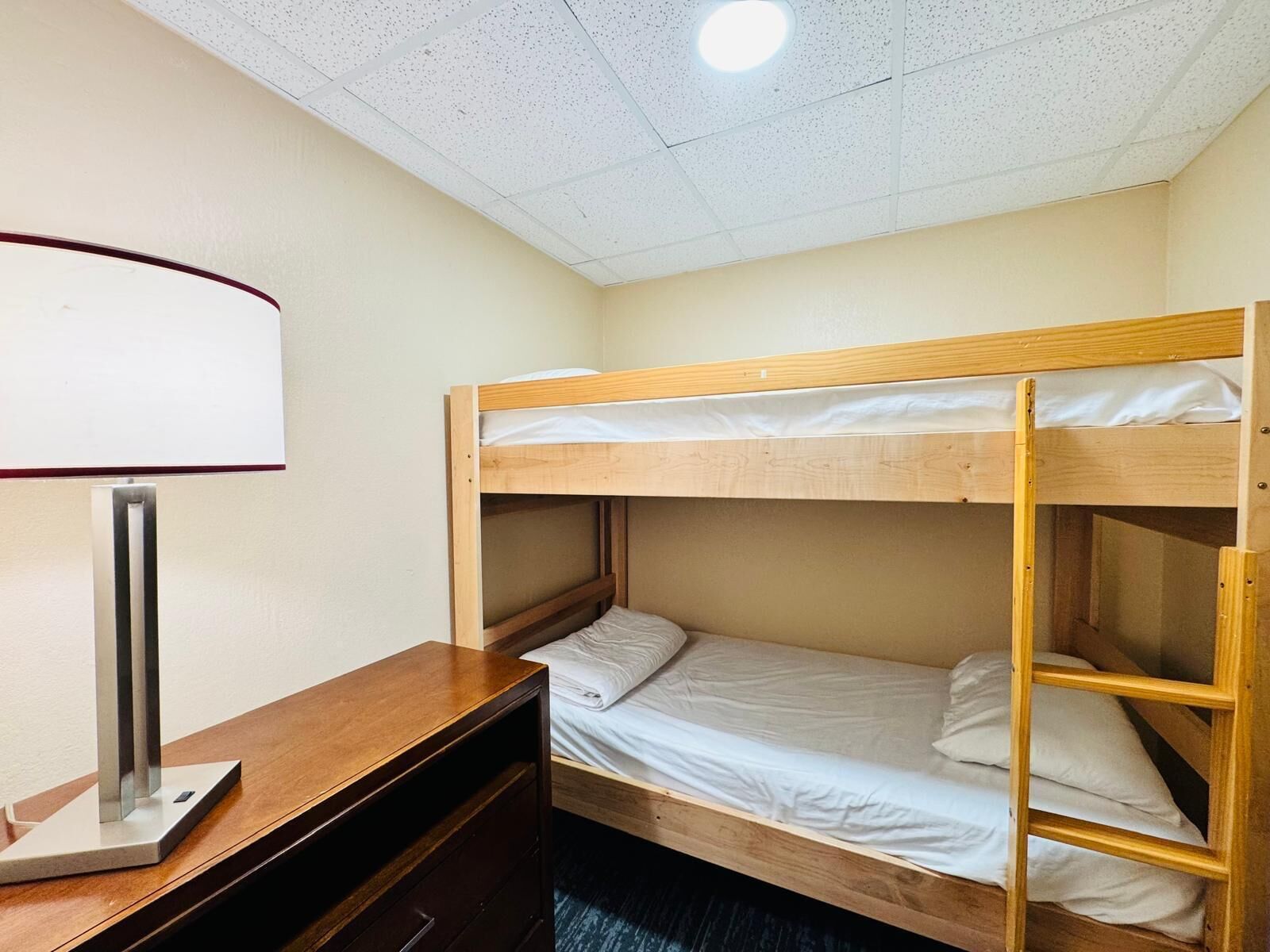 A bunk bed room with a desk and a lamp.