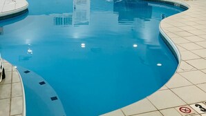 A swimming pool with a curved edge, tiled floor, and a no diving sign.