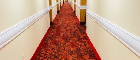 A long, narrow hallway with a patterned carpet and white walls.