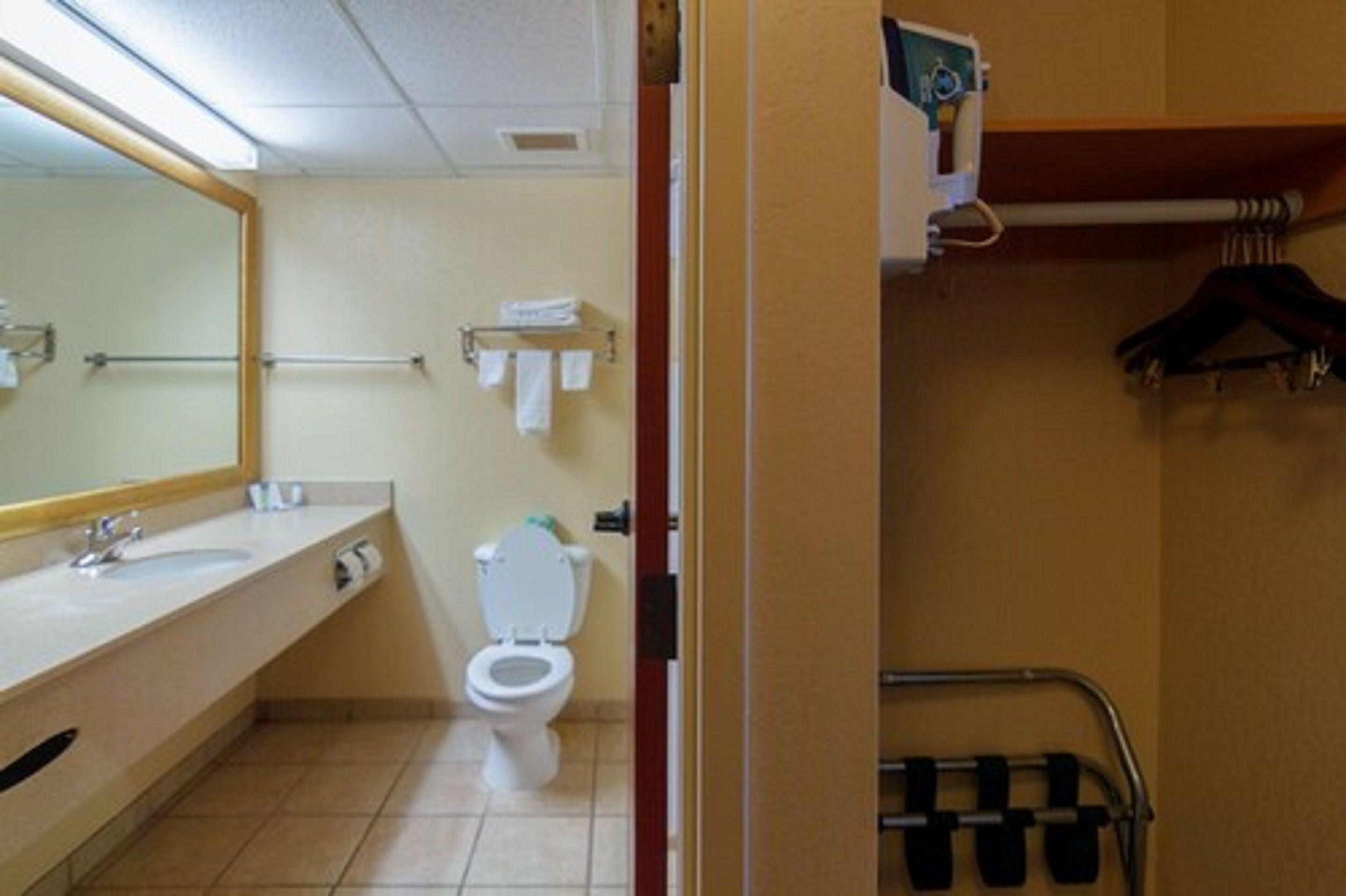 A bathroom with a sink, mirror, toilet, towel rack, and a hand dryer.