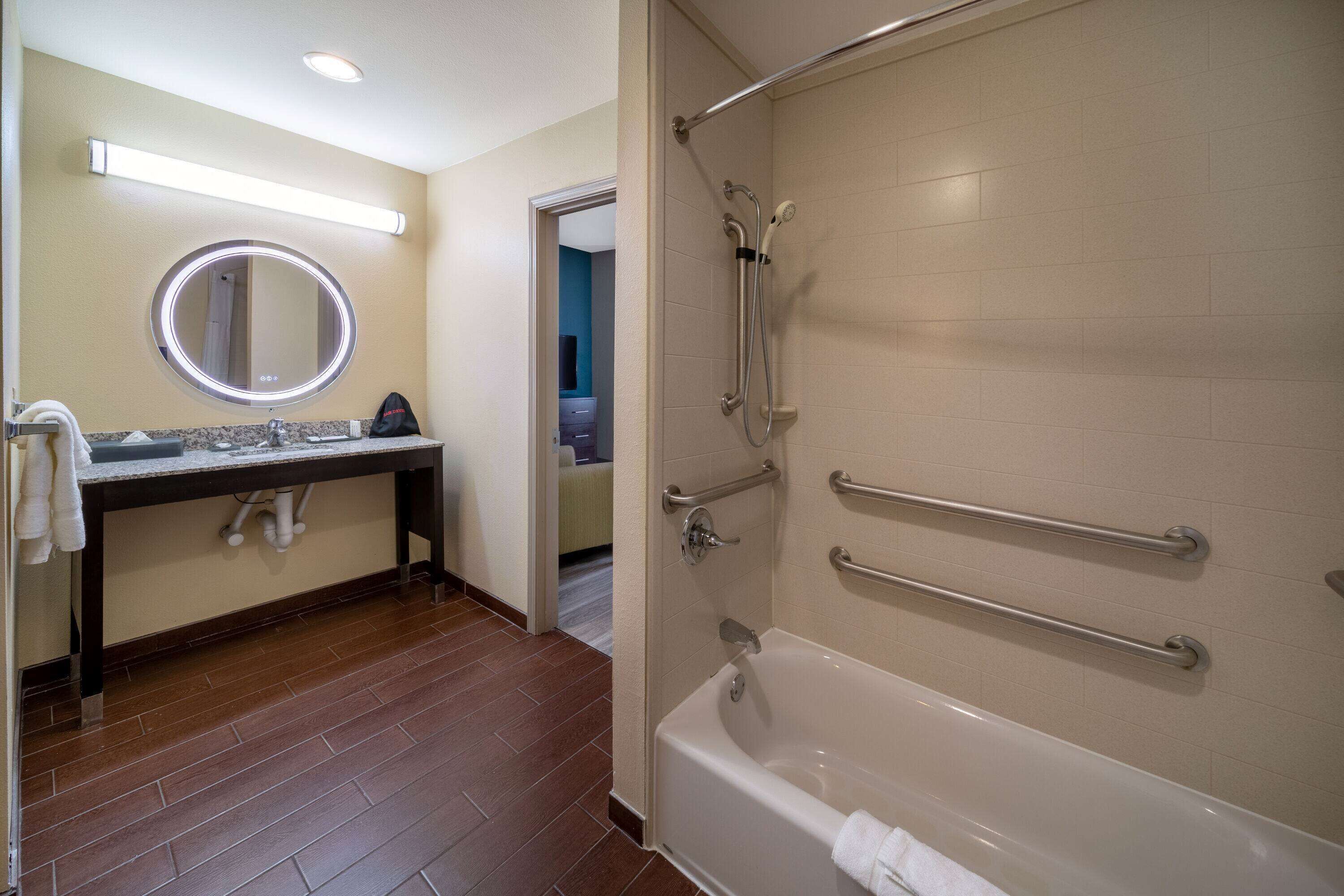 Un baño con bañera, lavamanos con espejo y zona de ducha.