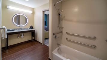 Un baño con bañera, lavamanos con espejo y zona de ducha.